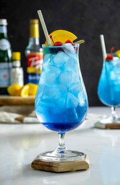 two glasses filled with blue liquid and ice