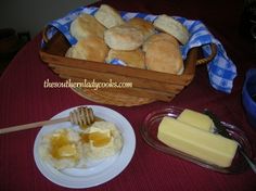 bread and butter are sitting on a table next to a basket with honeycombs