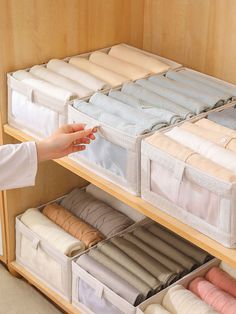 a person reaching for some folded clothes in a closet