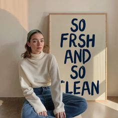 a woman sitting on the floor in front of a sign that says so fresh and so clean