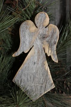 an angel ornament hanging from a pine tree