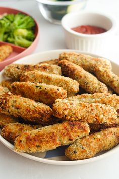 a white plate topped with fried food next to bowls of broccoli