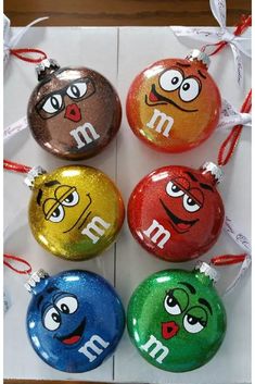 four ornaments with different colored faces on them, one has an m and the other is a