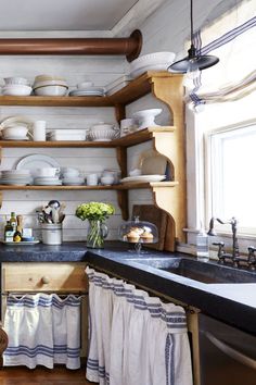 a kitchen filled with lots of white dishes and wooden shelves next to a stove top oven