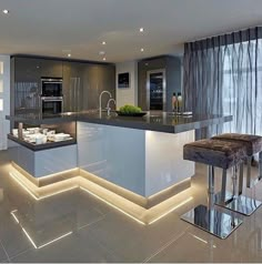 a modern kitchen with an island in the middle and lights on it's sides