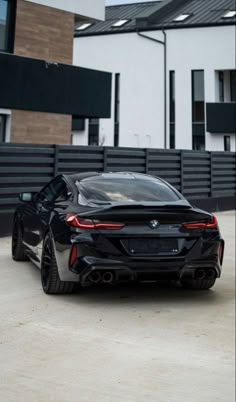 a black bmw sports car parked in front of a large building with a garage behind it