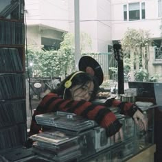 a woman with headphones on sitting in front of a record store counter filled with records