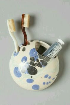 two toothbrushes are in a ceramic holder