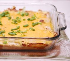 a casserole dish with green onions and cheese in it sitting on a table