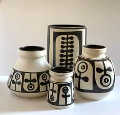 three black and white vases sitting next to each other on top of a table