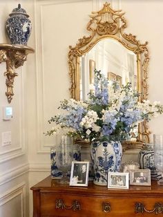 an ornate dresser with blue and white vases on top of it next to a mirror