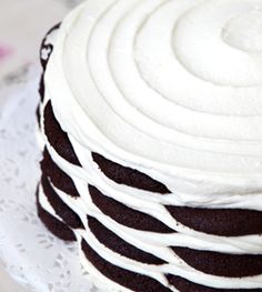 a close up of a cake on a doily with white frosting and chocolate swirls