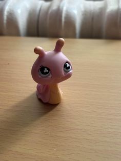 a little pink toy sitting on top of a wooden table