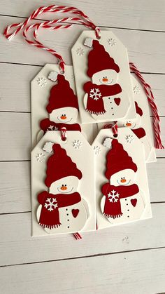 four tags with snowmen on them and candy canes next to them, all decorated in red and white