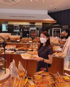 a woman wearing a face mask and holding a plate of food in front of some breads