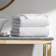 a stack of white towels sitting on top of a table next to a cup and saucer