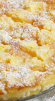 a cake with powdered sugar on top sitting in a glass pie dish, ready to be eaten