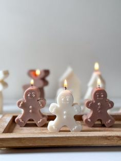 some candles are in the shape of gingerbreads on a wooden tray with white frosting