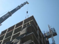 a crane is lifting concrete into place on top of a building that's under construction