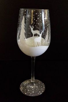 a wine glass with a reindeer design on the bottom and snowflakes around it