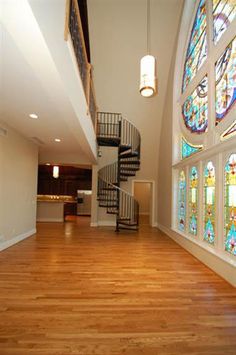 an empty room with stained glass windows and wooden floors in front of a spiral staircase