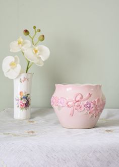 two vases with flowers in them sitting on a table next to a white cloth