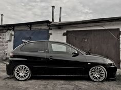 a small black car parked in front of a building