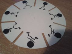 a clock with stick figures on it sitting on a table