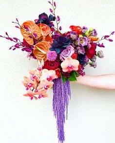 a woman holding a bouquet of flowers in her hand with purple and orange colors on it