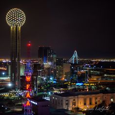 the city skyline is lit up at night, with lights on and buildings in the foreground