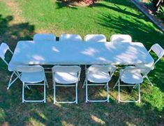 an outdoor table and chairs set up in the grass