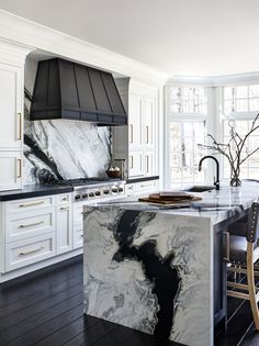 a kitchen with marble counter tops and white cabinets in the center, along with an island