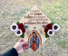 a hand holding up a paper cutout with flowers and an image of the virgin mary on it