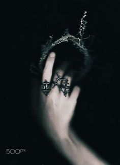 a person's hand with two rings in the middle of their fingers, and an image of three crosses on it