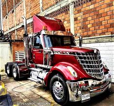 a red semi truck parked in front of a brick building