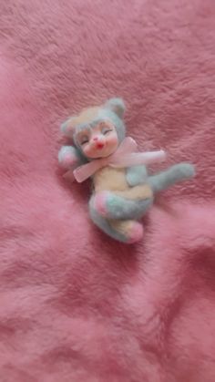 a small stuffed animal sitting on top of a pink blanket