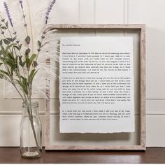 a vase with flowers next to a framed letter