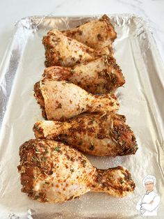 four pieces of chicken sitting on top of a foil pan covered in seasoning and spices