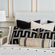 a white bed with black and gold pillows