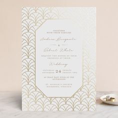 an elegant wedding card with gold foil on the front and back, sitting on a marble surface