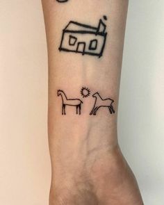 a small tattoo on the wrist of a person with a house and two horses in front of it