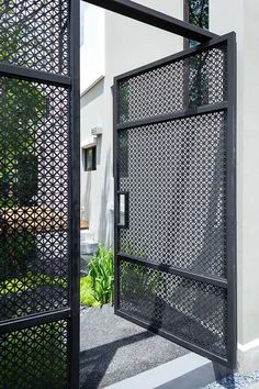 an iron gate is open on the side of a white building with plants in it