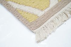 a yellow and white rug with fringes on the floor