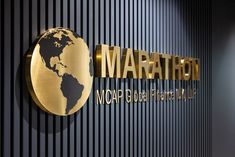 there is a gold sign that says marathon on the side of a wall with a world map