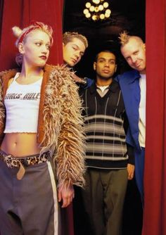 a group of people standing next to each other in front of a red curtain,