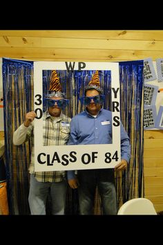 two men standing next to each other in front of a sign that says class of 84