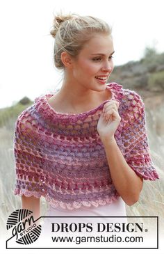 a woman wearing a pink and purple crocheted shawl in front of some tall grass