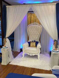 a white chair sitting on top of a wooden floor next to a blue and white curtain