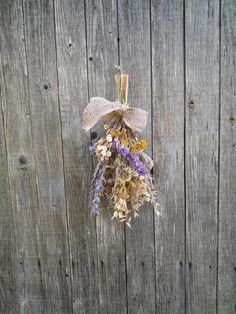 a bunch of dried flowers hanging on a wooden fence with a burlock tied to it