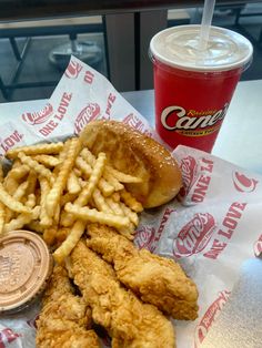 fried chicken and french fries on a table next to a cup of soda with a coin